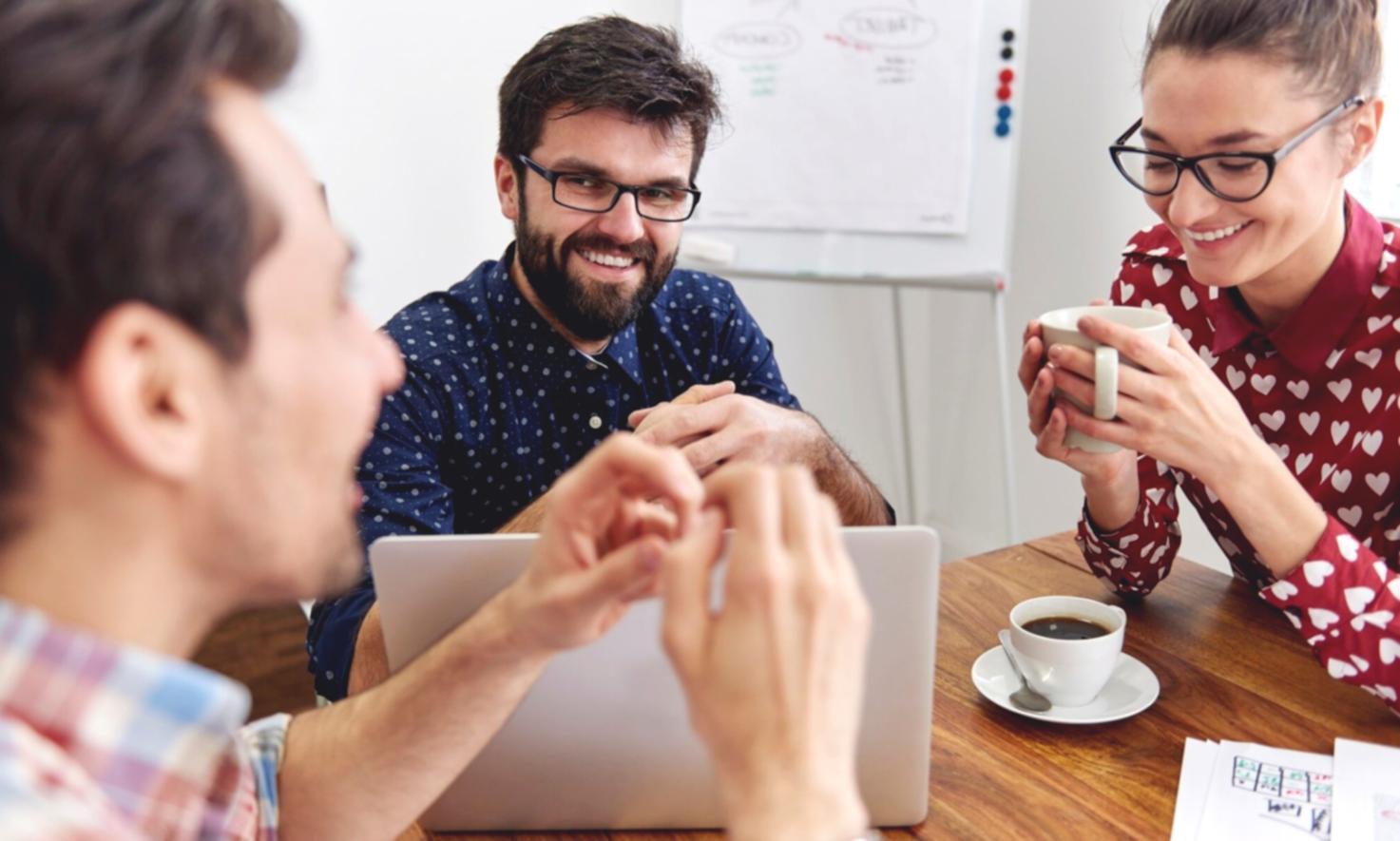Equipo de trabajo colaborando en análisis financiero con documentos y laptop sobre mesa de oficina